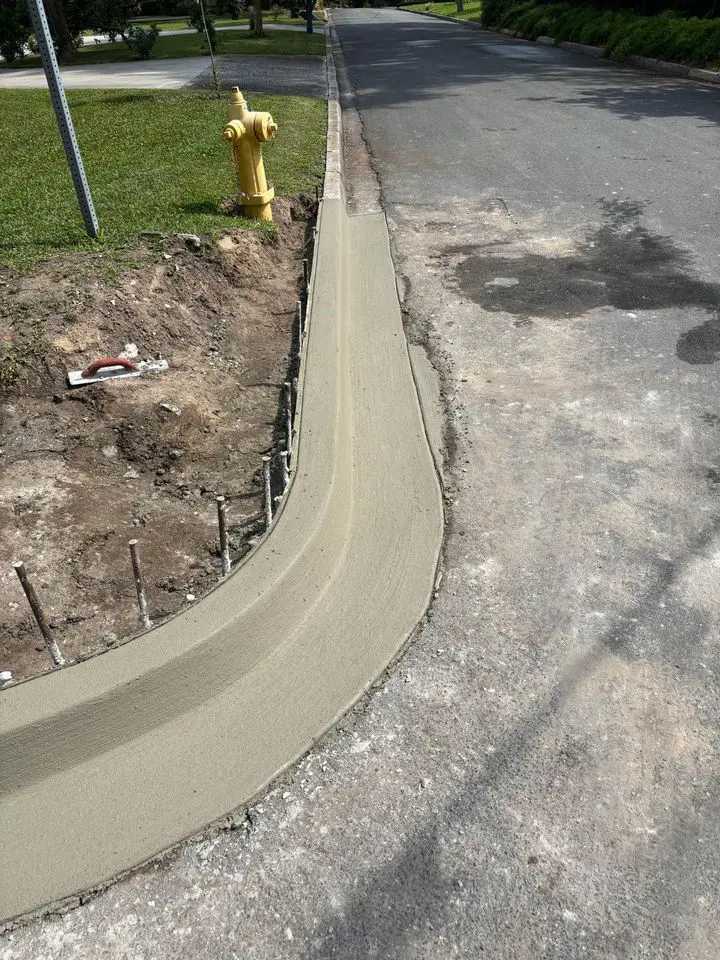 concrete curbing  repair on a corner. Just poured and finished. Next to an blacktop asphalt road