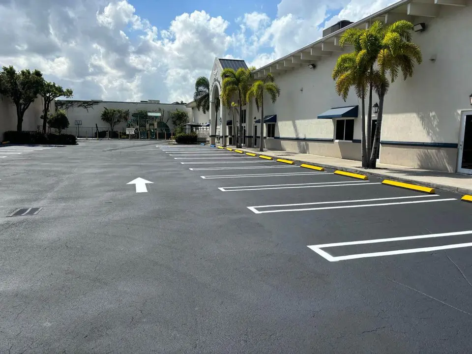 sealcoated and striped asphalt parking lot with parking lot lines and white arrows painted on parking lot surface