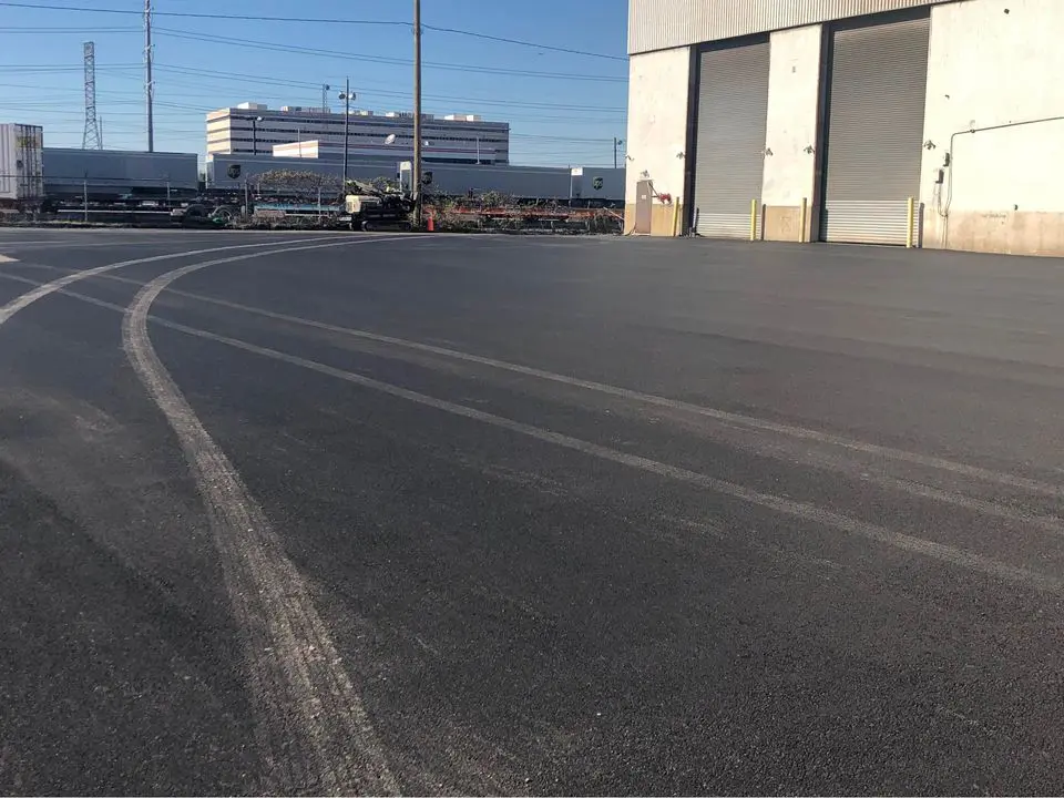 large industrial asphalt surface just been spray sealed with jet black asphalt sealer