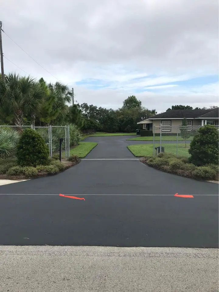 large asphalt driveway which has just been sealed with a jet black sealer. driveway in front of a large house in boca raton fl