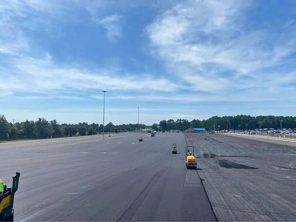 asphalt contractors in Boca Raton FL rolling freshly laid asphalt in a large commercial parking lot