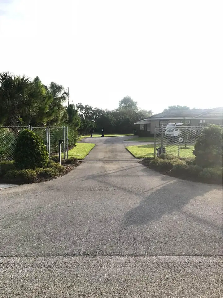 Freshly repaired asphalt driveway, with green grass on the edges in Boca Raton FL