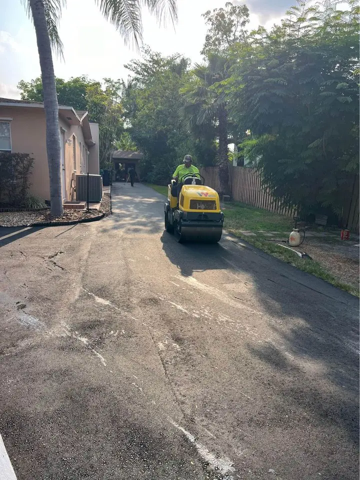 asphalt contractor in boca raton operating a roller. He is rolling and compacting some hot mix asphalt on a resurfacing job on a driveway