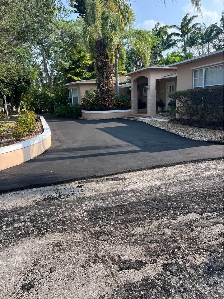 asphalt driveway for a home in boca raton which has had an asphalt overlay done on the old driveway. half completed with new asphalt in half of the photo, and old asphalt in the other half.