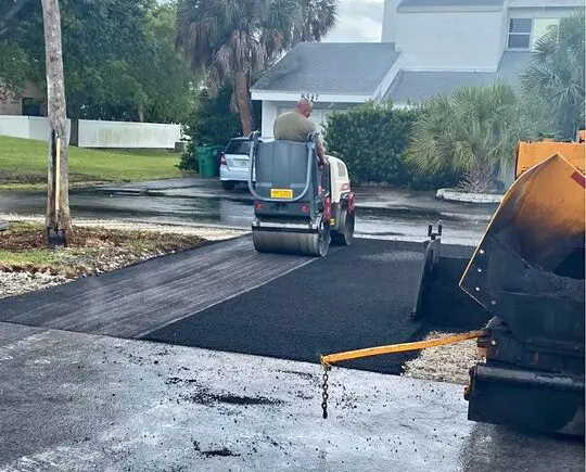 driveway in boynton beach fl being resurfaced by an asphalt contractor on a white asphalt roller