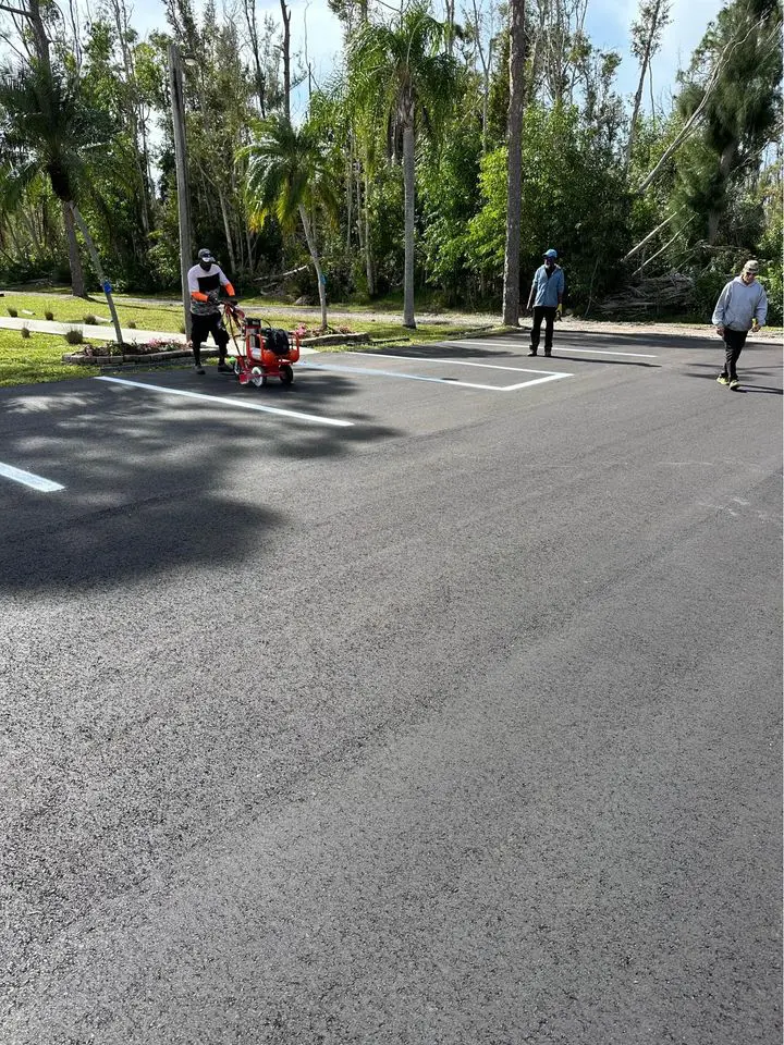 asphalt workers line striping a freshly laid asphalt parking lot for a community in Boca Raton FL