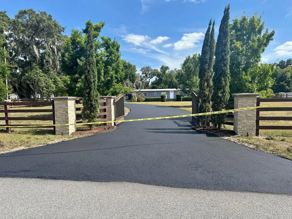 sealcoated asphalt driveway in front of an estate style home with a grand entrance in west boca raton