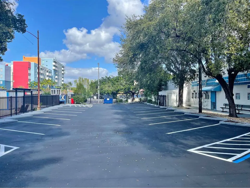 Selacoated asphalt parking lot in Delray Beach FL. Freshly painted line stripes in white, with white concrete wheel stops