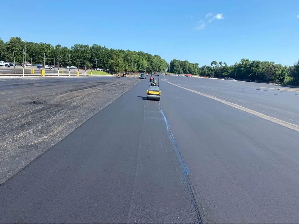 Asphalt overlay on a large road in South Florida. Asphalt contractor on a yellow asphalt roller compacting the freshly laid hot mix asphalt